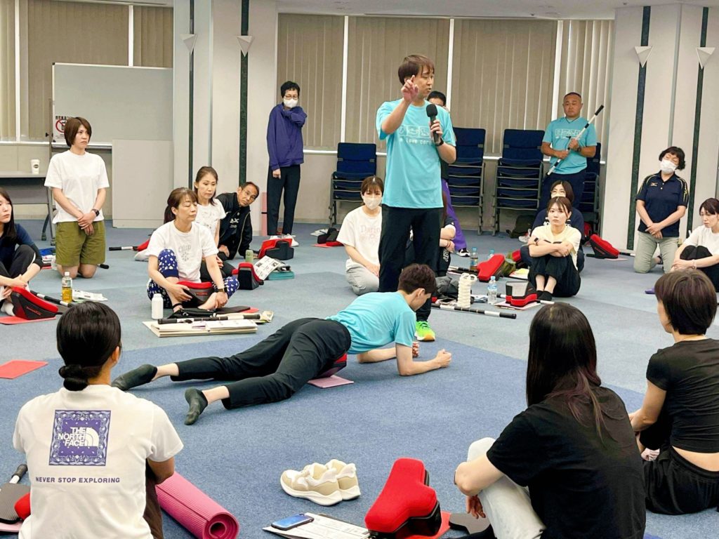 コアコンディショニングの勉強会で、スイングストレッチでスイングセブンを伝え、姿勢改善やゴルフなどスイング動作のパフォーマンスを向上させる方法を指導する様子。